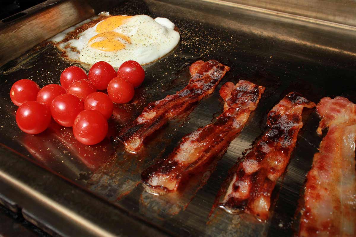 Frühstücksspeck mit Ei aus der Plancha