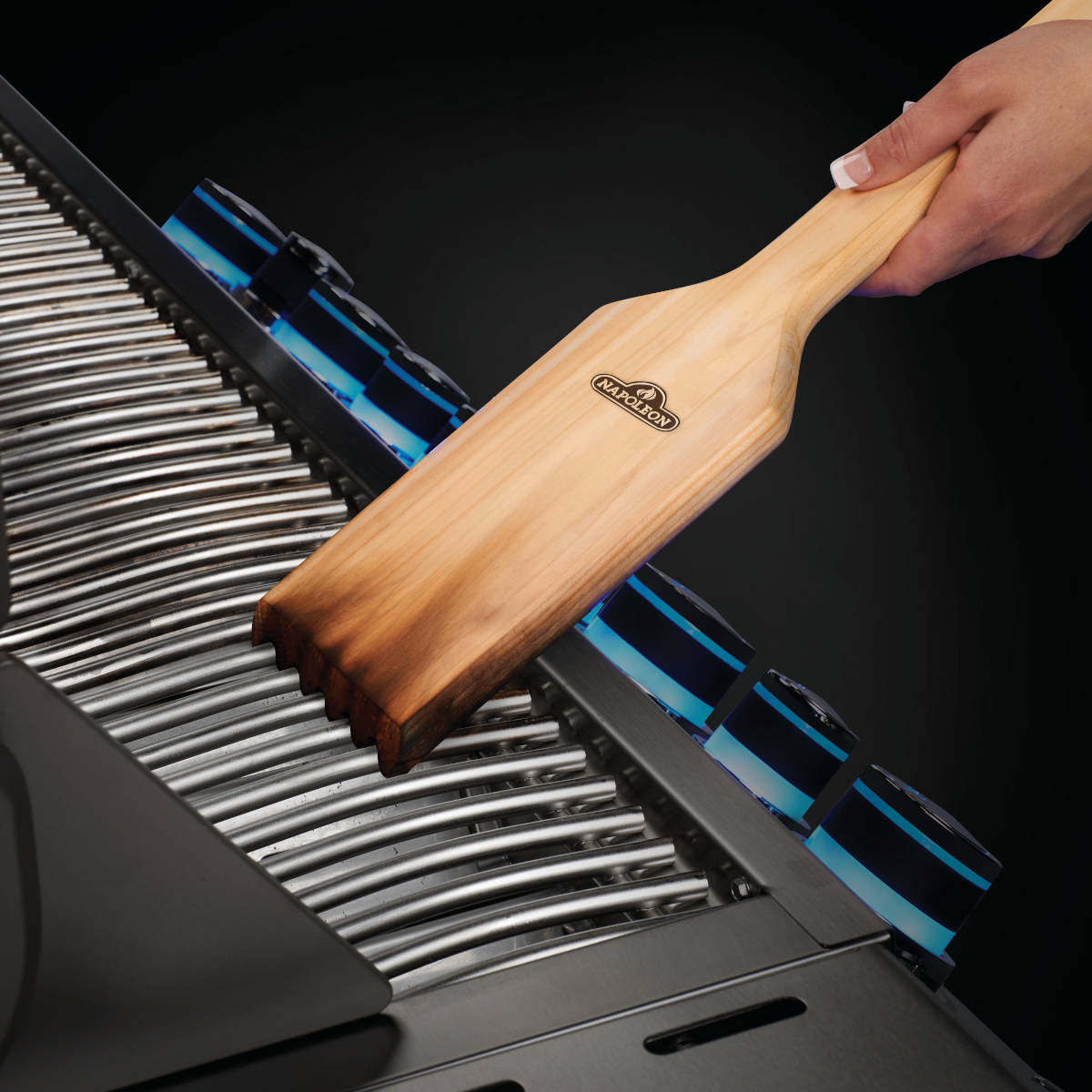 Reinigung des Grillrostes mit einem Schaber aus Holz